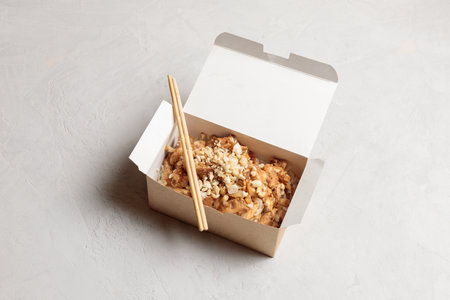 Street food, takeaway food or delivery of Chinese, Asian cuisine. Chicken in hot sauce, in a lunch box, on a light backgroundの写真素材