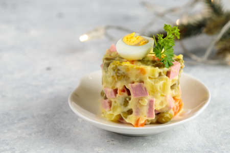 Buffet portion of olivier salad, garnished with parsley and half a quail egg. Close-up, selective focus, fir branch in the backgroundの写真素材