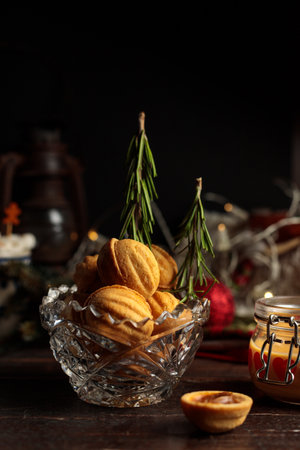 New Year's concept.Homemade cookies with boiled condensed milk, in the form of walnuts in a crystal bowl decorated with rosemary Christmas trees. Low key, close-upの写真素材