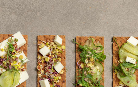 Finn crisp with sprouts, microgreens, cucumber, feta and seeds. Vegan snack. Close-up, top view, copy of the spaceの写真素材