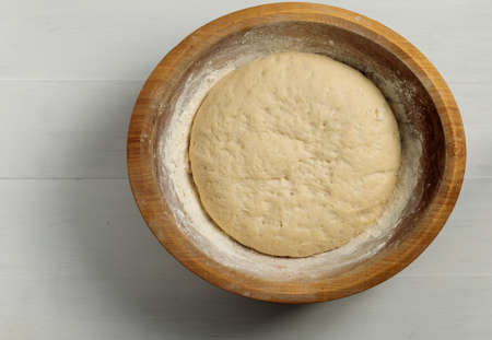 Preparation for baking bread, Easter cake, pie. Yeast dough in a wooden round bowl. close up, top...