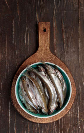 simple food, lunch at the seaside. Freshly caught raw fish, potato tubers and radishes. Still life, low keyの写真素材
