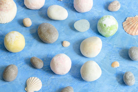 Japanese dessert mochi or ice cream balls, round buns on a blue background with shells and round sea pebbles. close-up, conceptual photoの写真素材