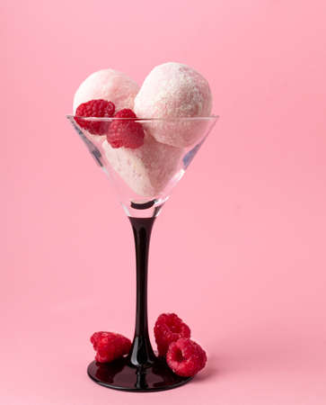 Japanese traditional dessert mochi or homemade ice cream balls in a tall glass decorated with raspberries. Vertical on pink backgroundの写真素材