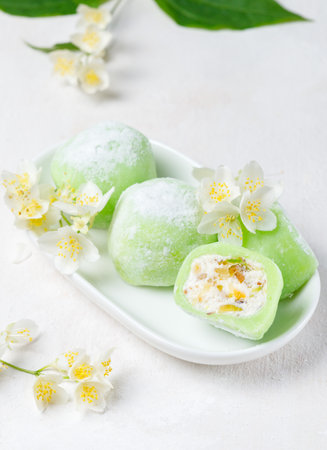 Japanese dessert mochi, or round cakes of green color with a soft viscous filling. Large canvas on a white background, with jasmine flowers.の写真素材
