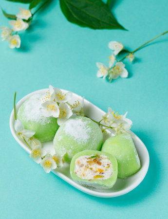 Japanese dessert mochi green. Close-up, with jasmine flowers on a blue background. Vertical frameの写真素材