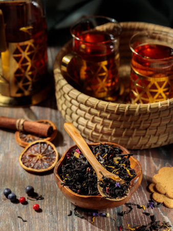 Fragrant fruit tea in glass cups in a wicker tray. Close-up on a wooden background, with berries and fruits.の写真素材