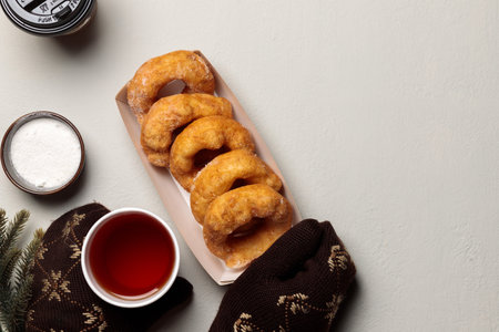 Hands in knitted mittens hold a drink in a disposable cup and a paper plate with donuts. Copy of the spaceの写真素材
