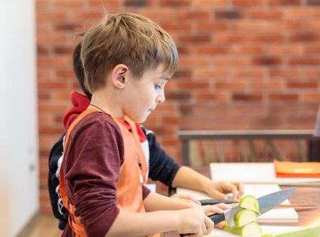 The boy is chopping vegetables. Culinary childrens studio. Portrait, selective focus.の写真素材