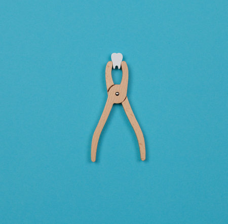 Childrens dental play set. Wooden tongs with a toy tooth. Blue background, copy spaceの写真素材