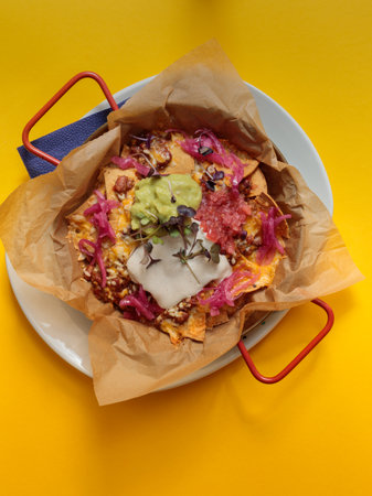 baked nachos with sauce in a frying pan. On a yellow background, top view.の写真素材