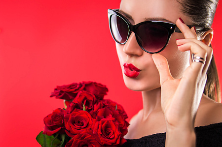 Beautiful woman in sunglasses holding rosesの写真素材