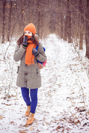 Woman with a backpack walking through winter forest.の写真素材