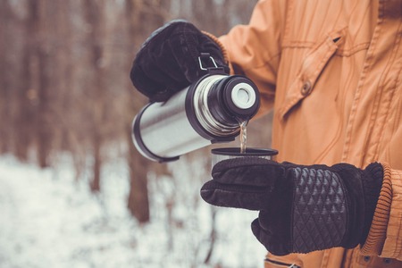 Man pours tea out of cup . Winter forest. Close-upの写真素材