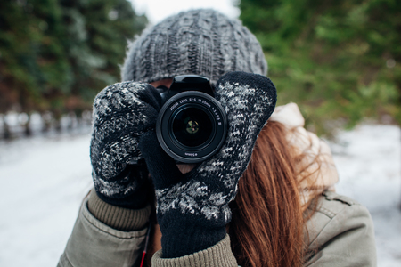 Young photographer takes pictures of winter forest with a cameraの写真素材