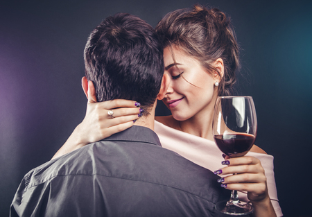 Couple celebrating Valentines day drinking red wine on black backgroundの写真素材
