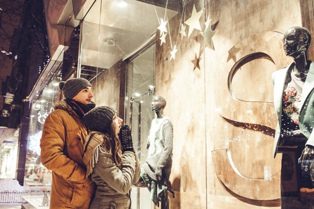 Young couple walking in the city center and window-shopping at night. Valentine's day salesの写真素材
