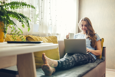 Young pretty woman using her laptop sitting in the livingroomの写真素材