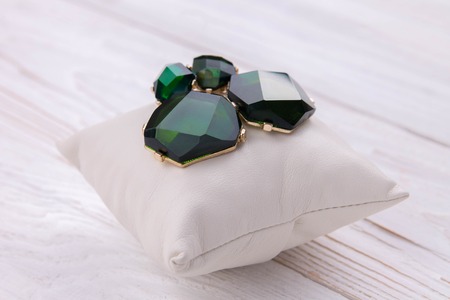 Gold earrings with emerald on the pillowの写真素材