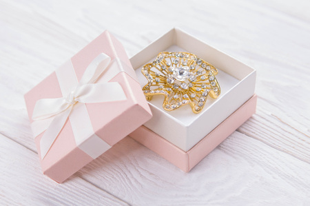 Gold brooch in the gift box on white wooden backgroundの写真素材
