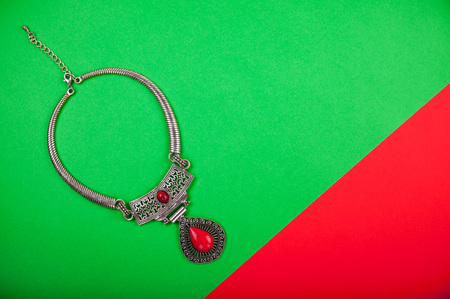 Indian or Turkish necklace with a red stone on red and green backgroundの写真素材