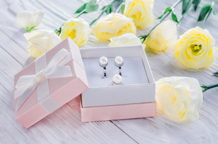 Pearl earrings with flowers in the gift box on wooden background
