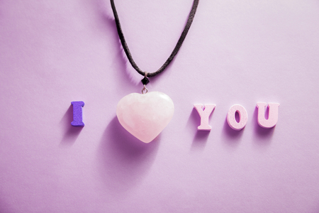 I love you lettering with a heart necklace on purple paper background. Valentine's day concept.の写真素材