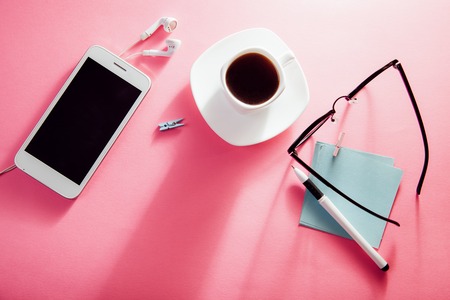 Coffe break of an office employee. Working with a cup of coffee and snacks, using a smartphoneの写真素材