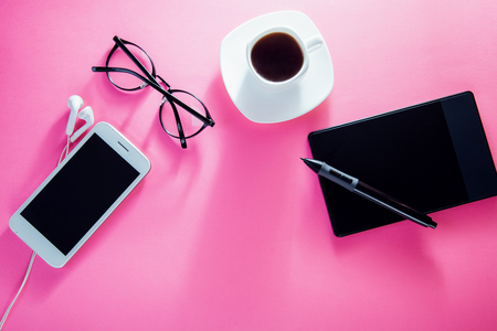 Coffe break of a designer. Working with a cup of coffee and using a pen tablet on pink backgroundの写真素材
