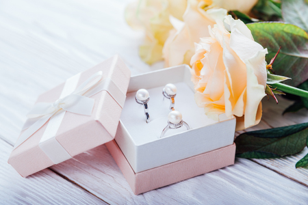 Pearl earrings in the gift box with roses on wooden backgroundの写真素材