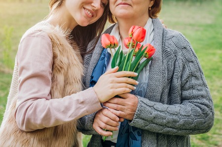 Middle-aged mother and her daughter hugging in blooming spring gardenの写真素材
