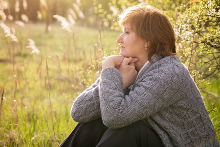 Middle-aged woman relaxing in spring garden at sunsetの写真素材