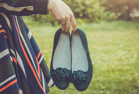 Woman holds a pair of green suede flatsの写真素材