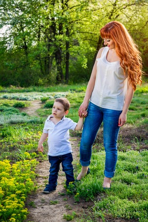 Young mother walks with her little son in spring garden. Mother's Day conceptの写真素材