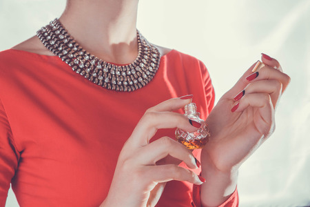 Woman in red dress applying perfume on her wristの写真素材
