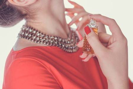 Woman in red dress applying perfume on her neckの写真素材