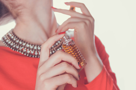 Woman in red dress applying perfume on her neck