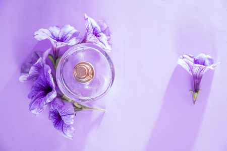 Bottle of perfume with flowers on purple backgroundの写真素材