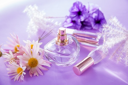 Bottles of perfume with flowers on purple backgroundの写真素材
