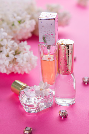 Bottles of perfume with white lilac on pink backgroundの写真素材