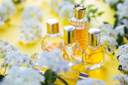 Bottles of perfume with white flowers on yellow backgroundの写真素材