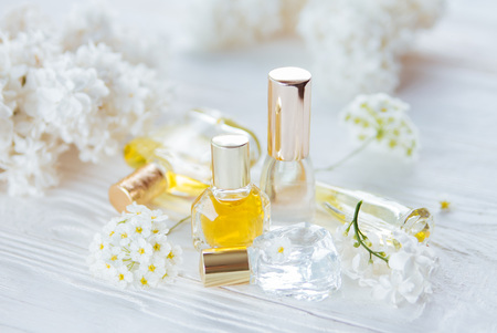 Bottles of perfume with white flowers on wooden backgroundの写真素材