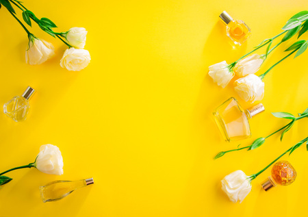 Bottles of perfume with eustoma flowers on yellow background