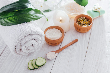 Spa essentials including candle, salt, herbs and white clay on wooden backgroundの写真素材
