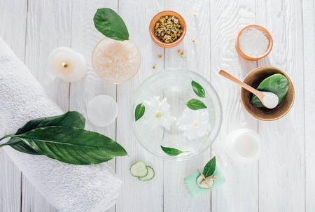 Spa essentials including candle, salt, herbs and white clay on wooden backgroundの写真素材
