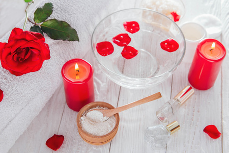 Spa essentials including candle, salt, roses and white clay on wooden backgroundの写真素材