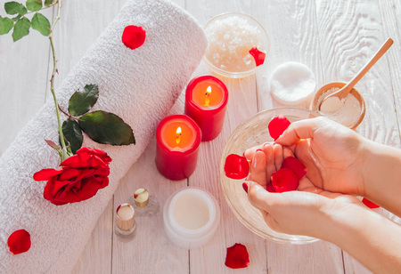 Female hands in bowl with rose water on wooden table. Skincare and spa conceptの写真素材