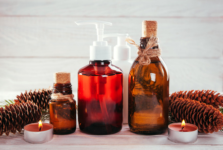 Fir tree and cones organic oils with candles on wooden background. Organic cosmetics conceptの写真素材
