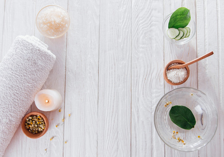 Spa essentials including candle, salt, herbs and white clay on wooden backgroundの写真素材