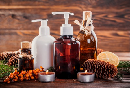 Fir tree and cones organic oils with lemon and sea buckthorn extracts on wooden background. Organic cosmetics conceptの写真素材